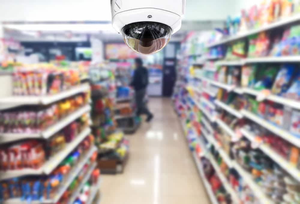 Image is of a surveillance camera monitoring a retail store aisle, concept of a theft charge and how security footage may be reviewed during a criminal investigation.