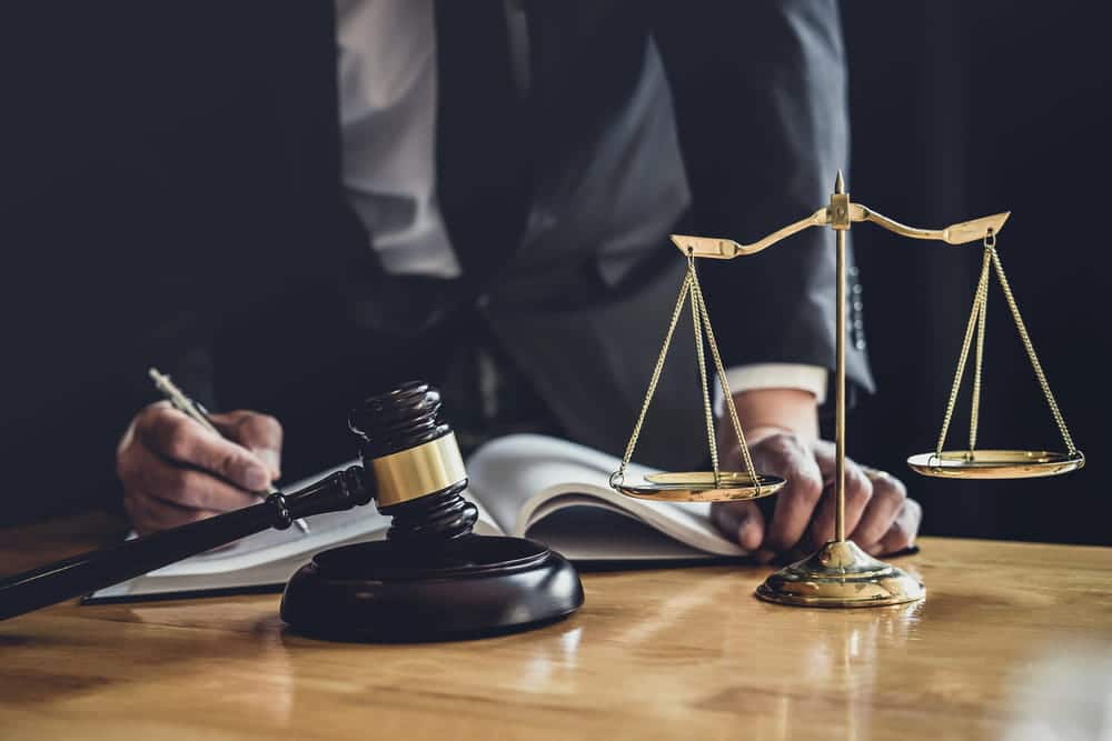 Image is of a lawyer writing at a desk with a gavel and scales of justice, concept of an arson lawyer preparing a legal defense