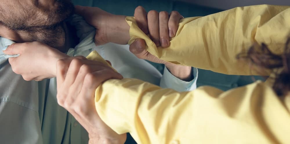 Image is of a person grabbing another individual during a physical altercation, concept of assault and batter lawyer