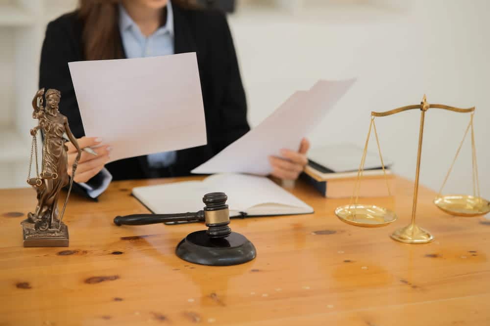 Image is of a legal professional reviewing documents beside courtroom symbols, concept of a burglary lawyer preparing a defense strategy.