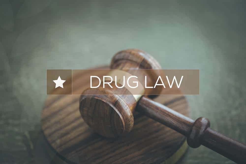 Image is of a courtroom gavel close up with legal text overlay, concept of drug distribution lawyer handling serious charges