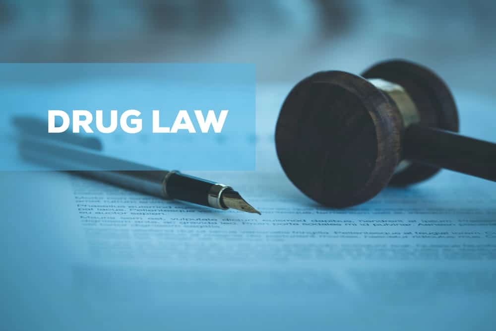 Image is of a gavel and legal document with a pen, concept of drug distribution lawyer reviewing case details