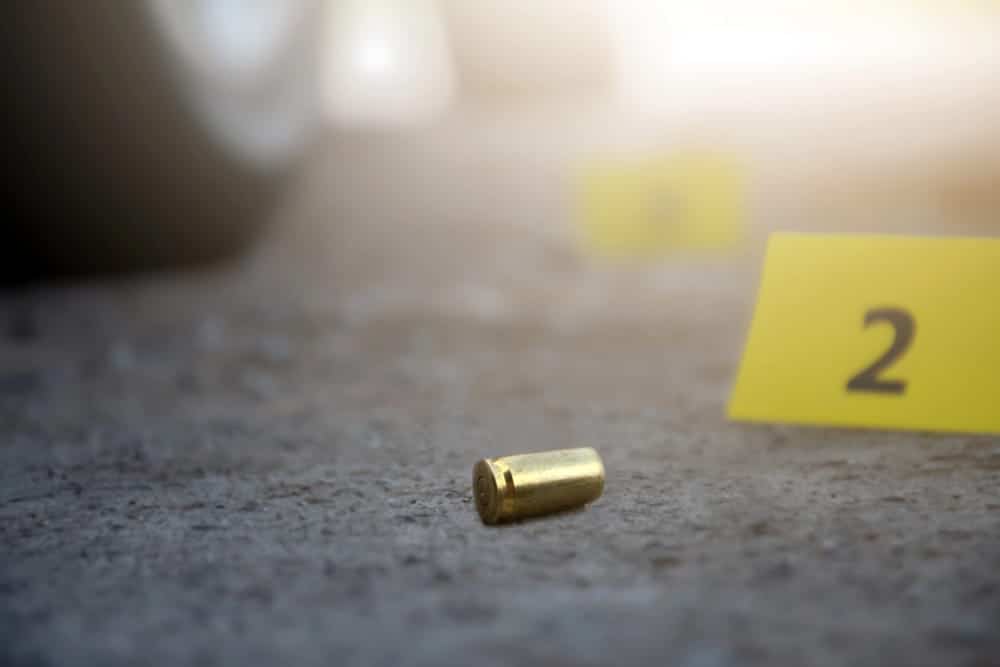 Image is of a bullet casing on the ground near an evidence marker, concept of gun crimes lawyer