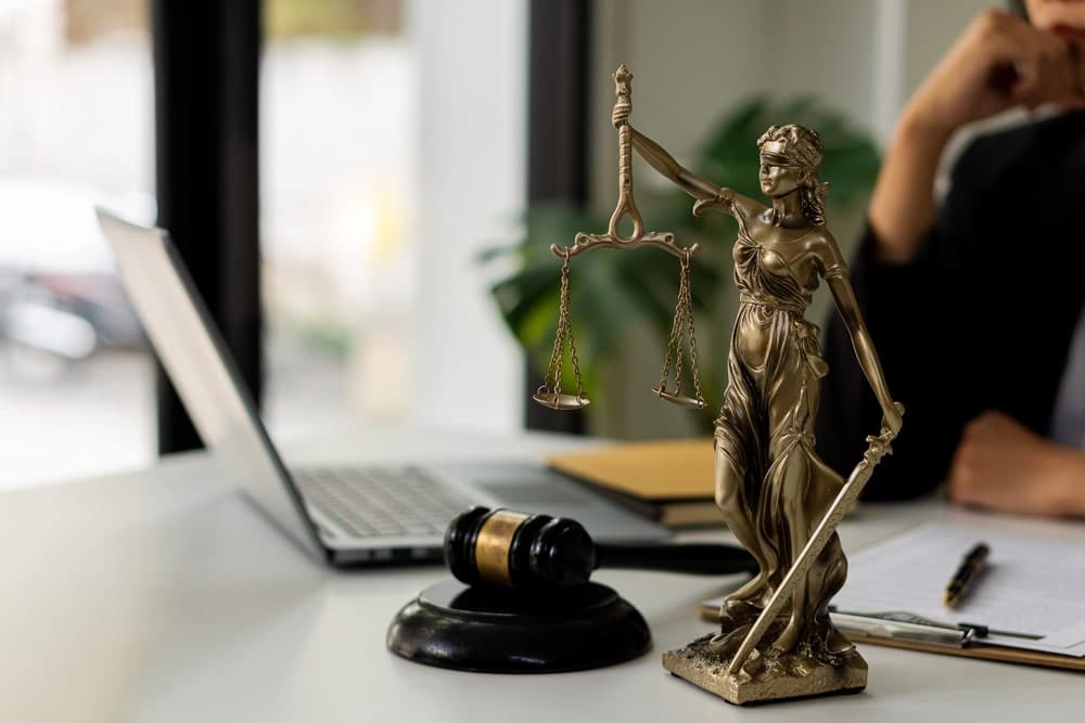Image is of a Lady Justice statue placed on a desk in a law office, concept of gun crimes lawyer