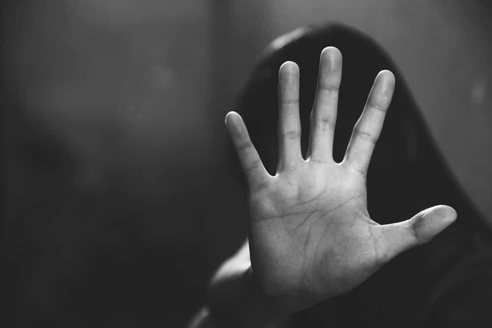 Image is of a person raising their hand in distress, concept of rape defense lawyer addressing serious allegations and impact