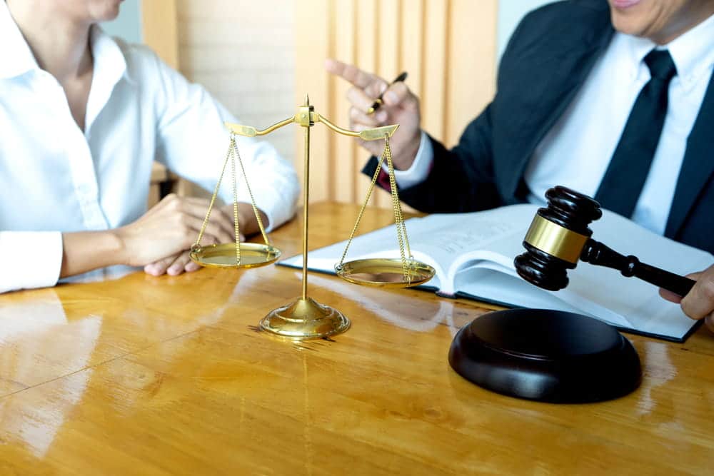 Image is of a lawyer discussing documents with a client at a desk, concept of rape defense lawyer providing legal guidance