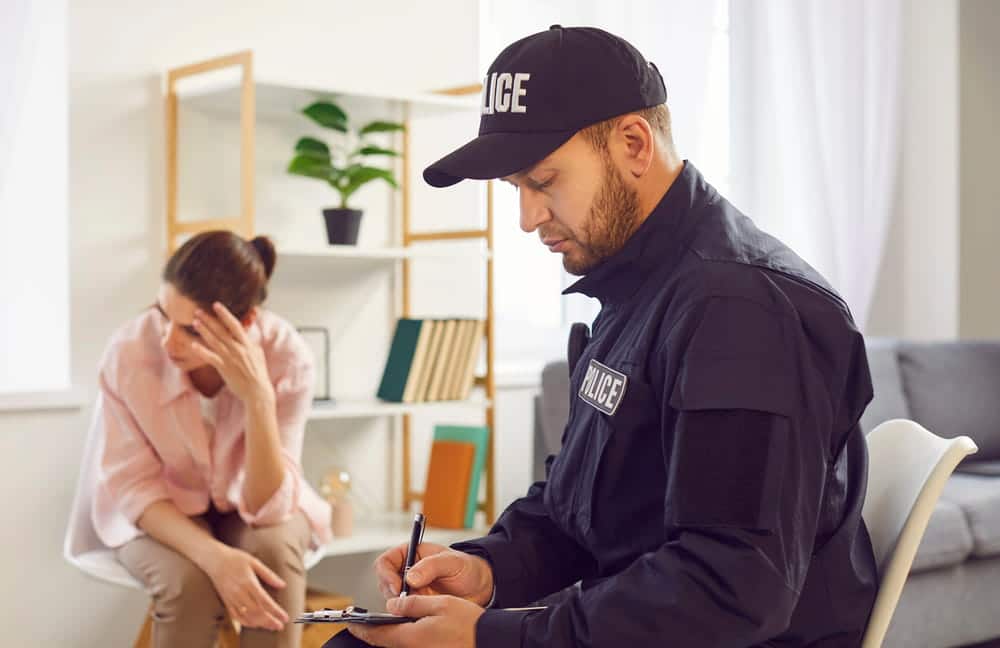 Image is of a police officer taking notes while speaking with a woman, concept of sex crimes lawyer reviewing statements and case details