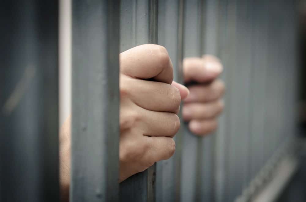 Image is of hands gripping jail bars, symbolizing detention and legal consequences, concept of sexual assault lawyer defending against serious charges