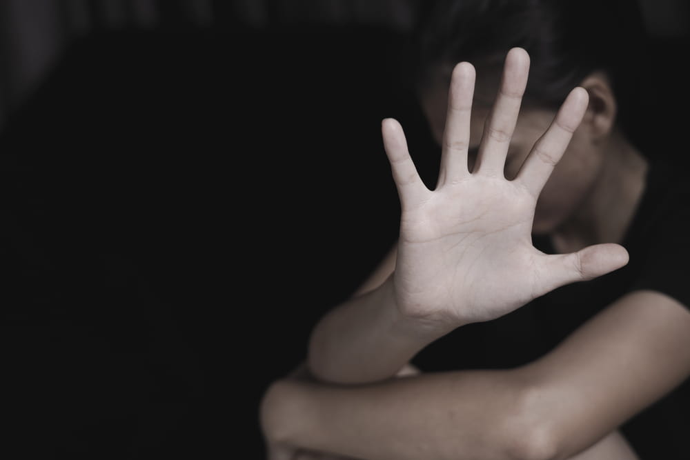 Image is of an individual raising their hand in a defensive gesture, representing fear and protection, concept of sexual assault lawyer handling sensitive allegations
