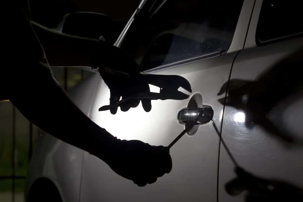 Image is of a suspected vehicle break-in involving theft tools near a car door, concept of a theft crimes lawyer handling auto theft allegations