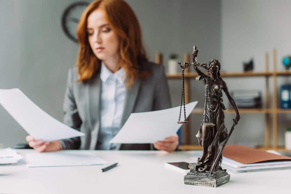 Image is of an attorney working at a desk with legal documents and scales of justice, concept of a theft crimes lawyer handling theft allegations