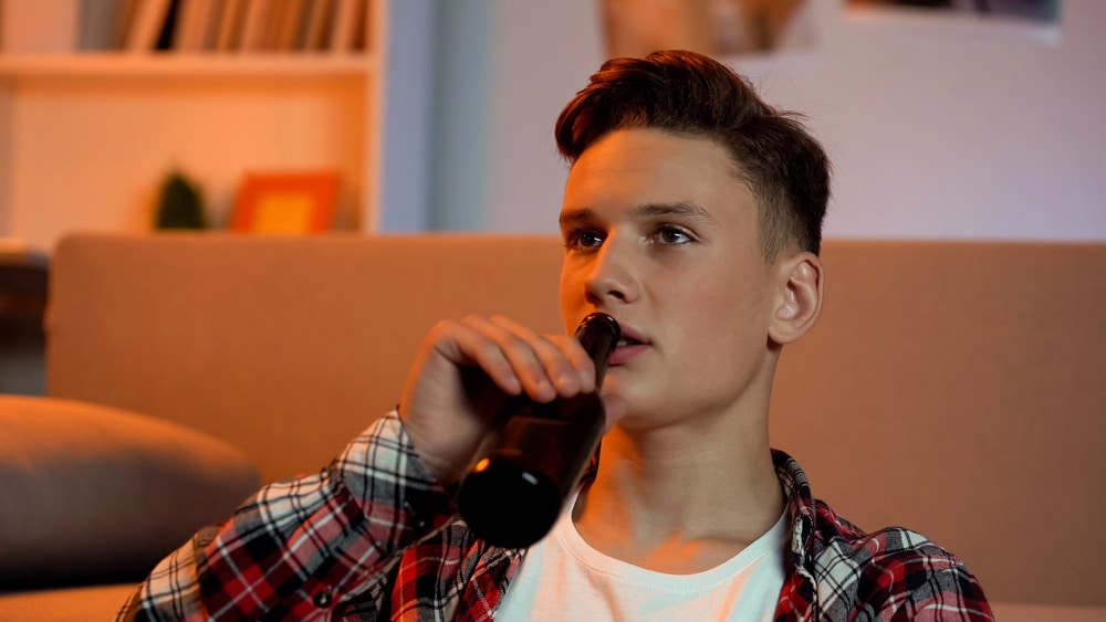 Image is of a young person drinking from a bottle at home, concept of Clinton underage lawyer for underage DUI concerns.