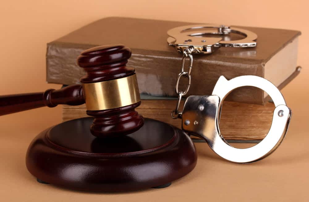 Image is of a gavel, law book, and handcuffs on a desk, concept of Knoxville criminal defense lawyer.
