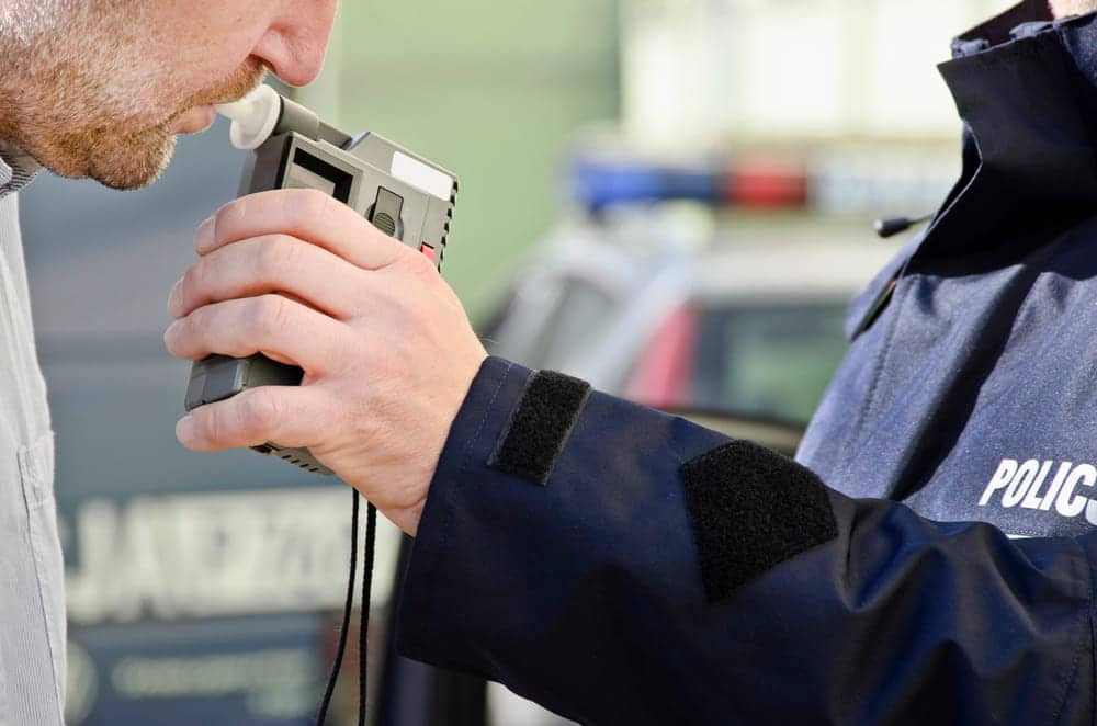 Image is of a police officer administering a breath test during a traffic stop, concept of Knoxville DUI defense lawyer.