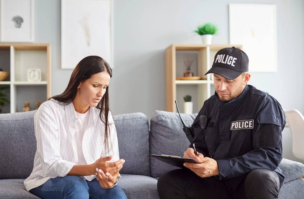 Image is of a police officer taking a statement from a woman in a home setting, concept of Knoxville domestic violence lawyer.