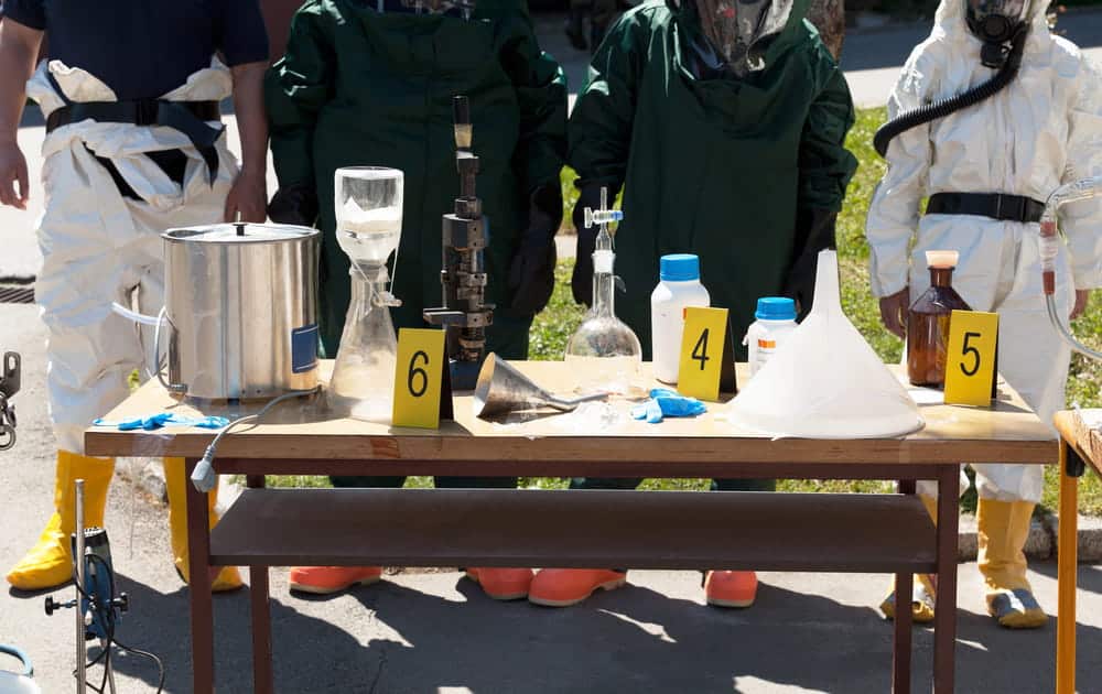 Image is of investigators collecting laboratory equipment and evidence during a drug manufacturing investigation under Tennessee law.