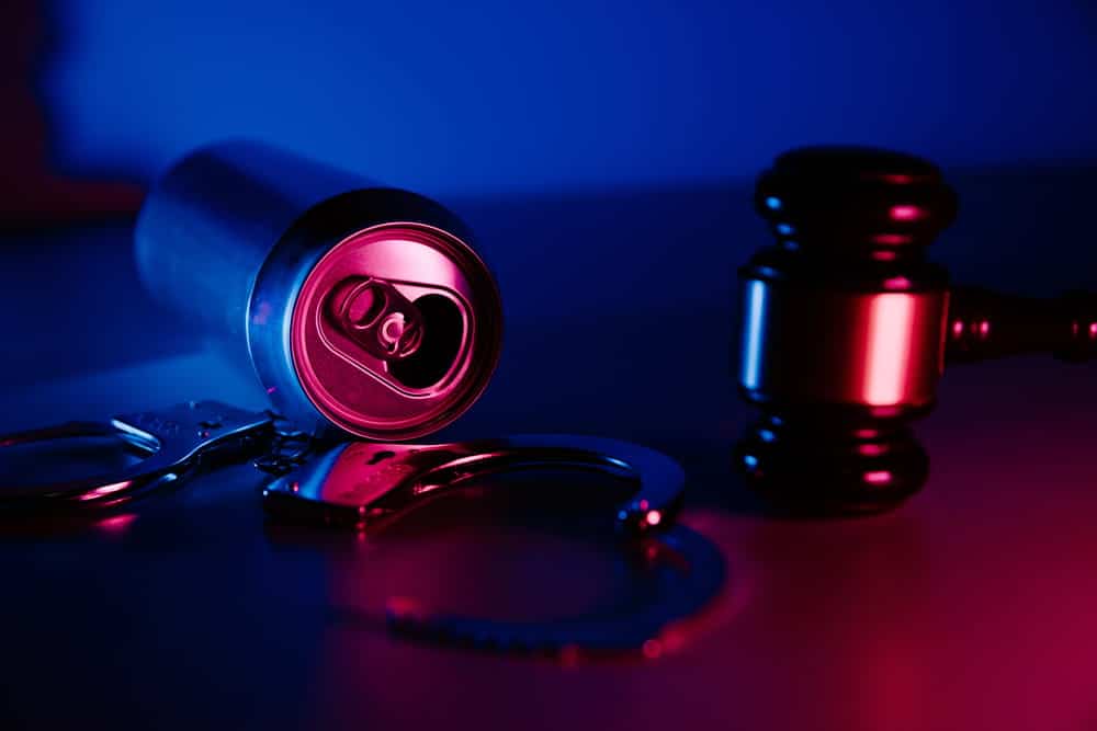 Image is of handcuffs, an alcohol can, and a judge’s gavel, concept of how a DUI affect employment after a conviction.