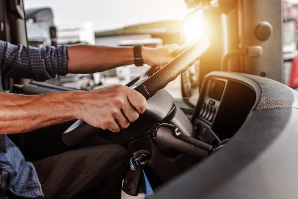 Image is of a CDL driver behind the wheel of a commercial truck, concept of DUI license consequences.