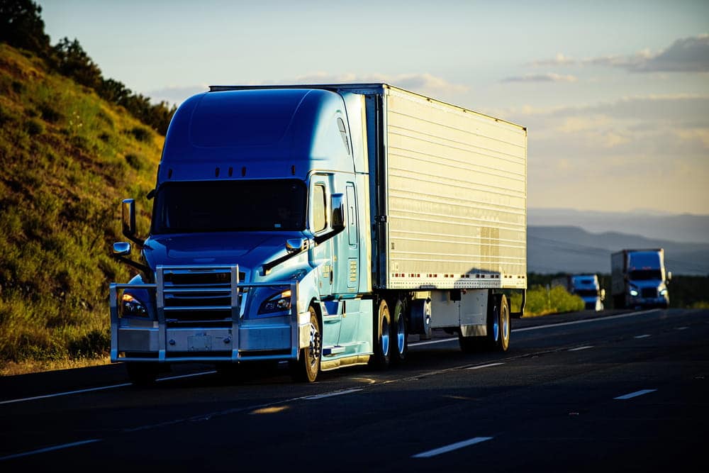 Image is of a commercial semi truck traveling on a highway, concept of CDL driver license consequences after DUI.