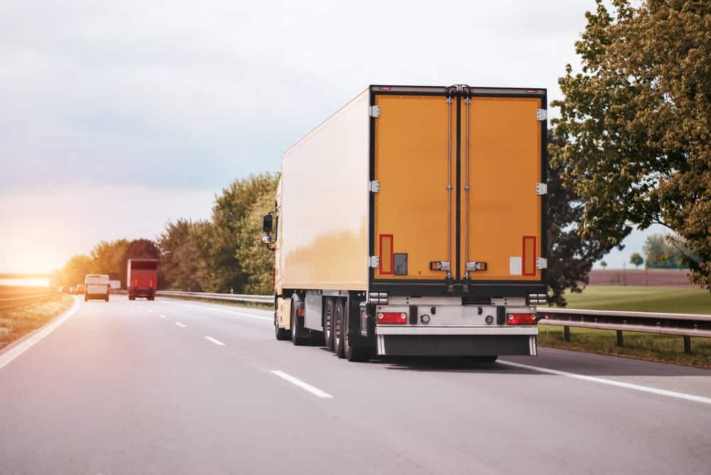 Image is of a commercial truck traveling on a highway, concept of CDL driver license consequences after DUI.