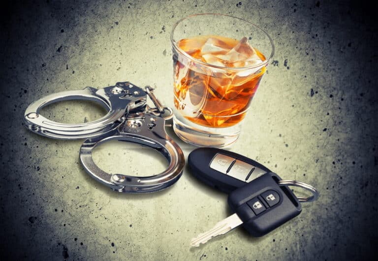 Image is of alcohol, vehicle keys, and handcuffs representing criminal charges and felony DUI penalties involved in Tennessee DUI cases