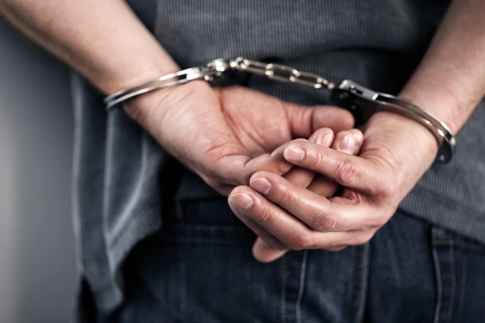 Image is of a person standing in handcuffs, concept of what may happen after a DUI arrest in Clinton.
