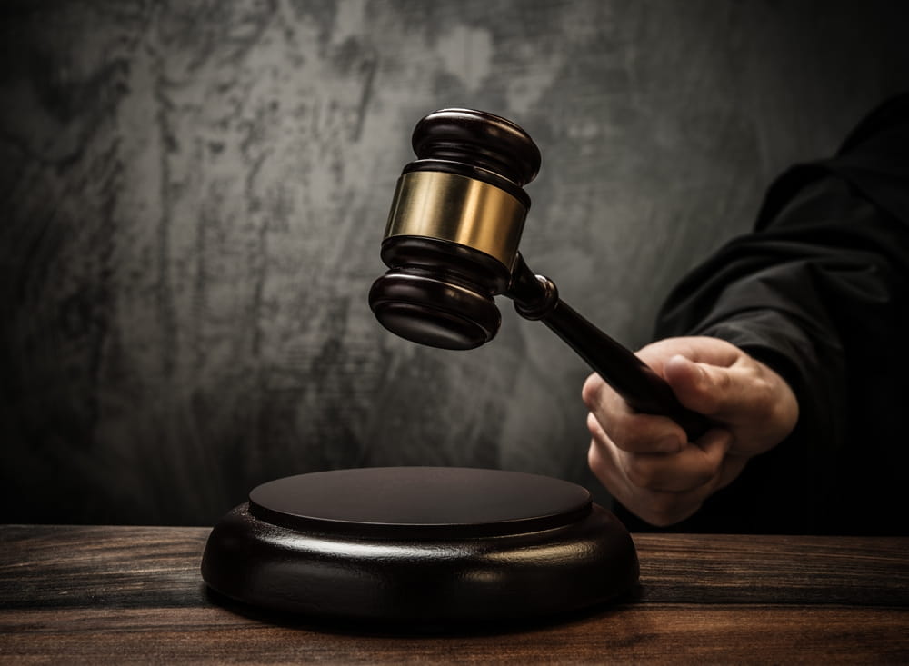 Image is of a judge holding a wooden gavel above a sounding block, concept of criminal court proceedings involving a drug manufacturing charge in Clinton.