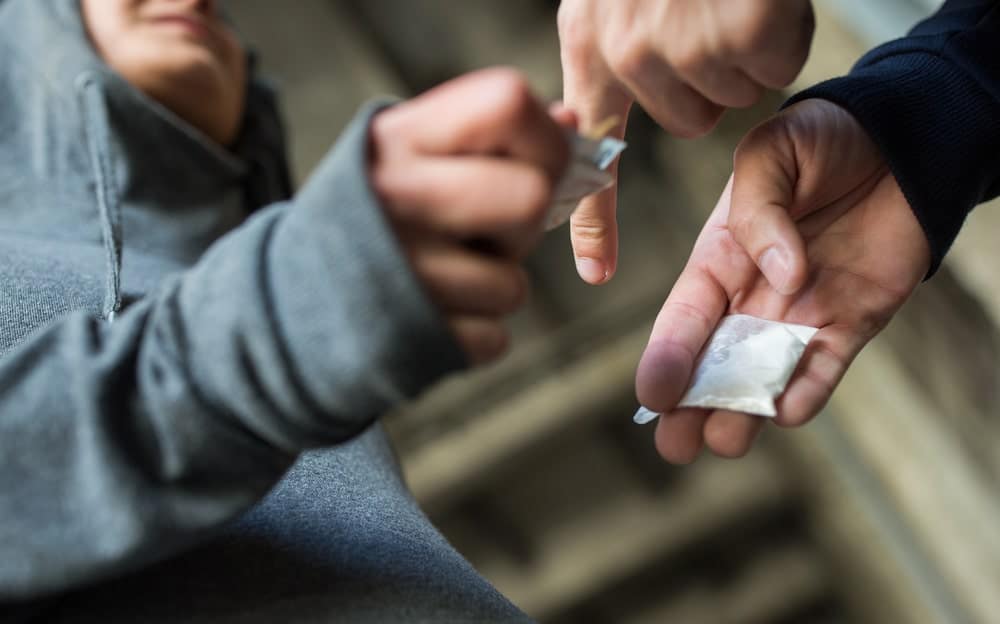 Image is of a suspected hand to hand drug transaction, concept of evidence prosecutors may use to prove drug distribution charges.