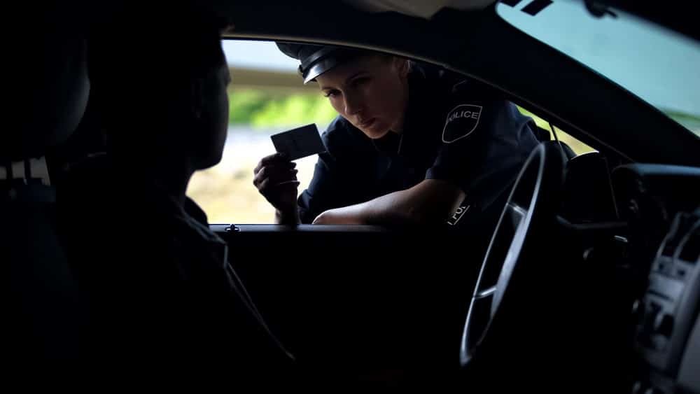 Image is of a police officer checking a driver's identification during a traffic stop, concept of police procedures following an underage DUI in Knoxville.